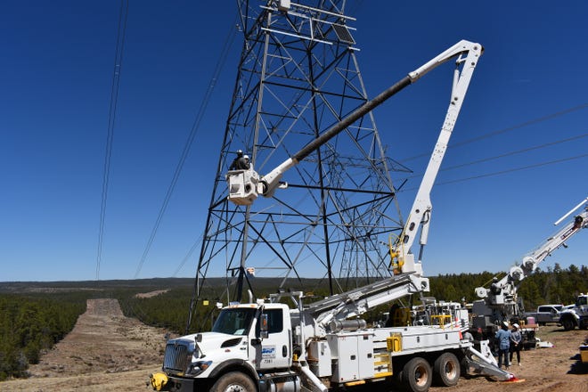 Crews for utility SRP install artificial intelligence-enabled cameras on transmission towers in forest areas east of Phoenix.